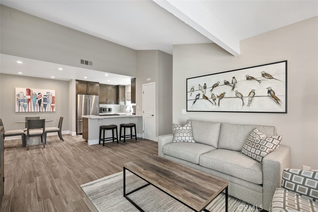 a living room with furniture and a dining table with wooden floor