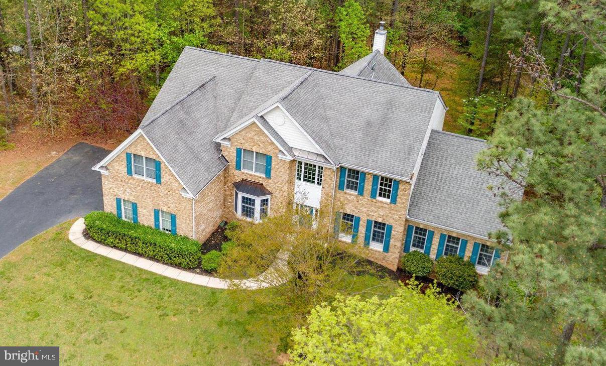 a aerial view of a house next to a yard with plants and large trees