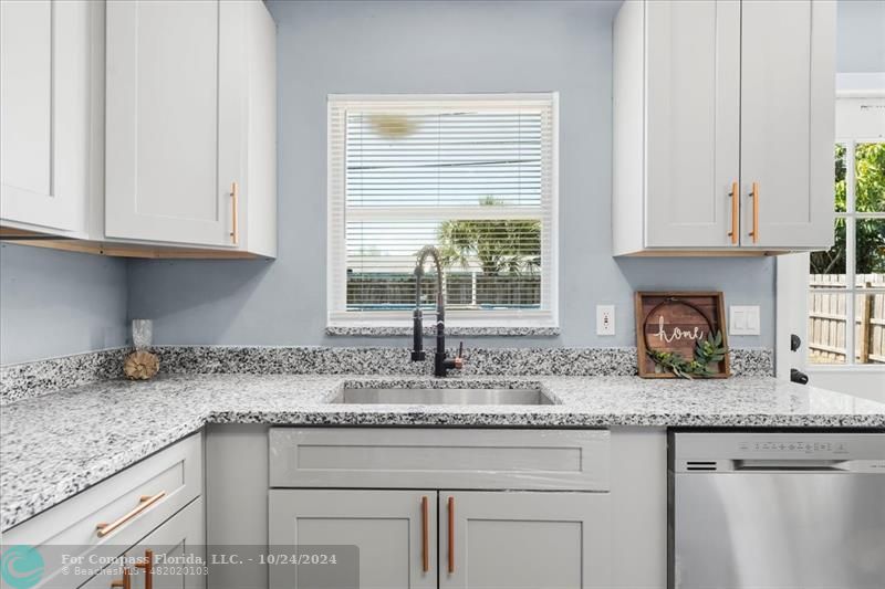 a kitchen with granite countertop white cabinets and a window