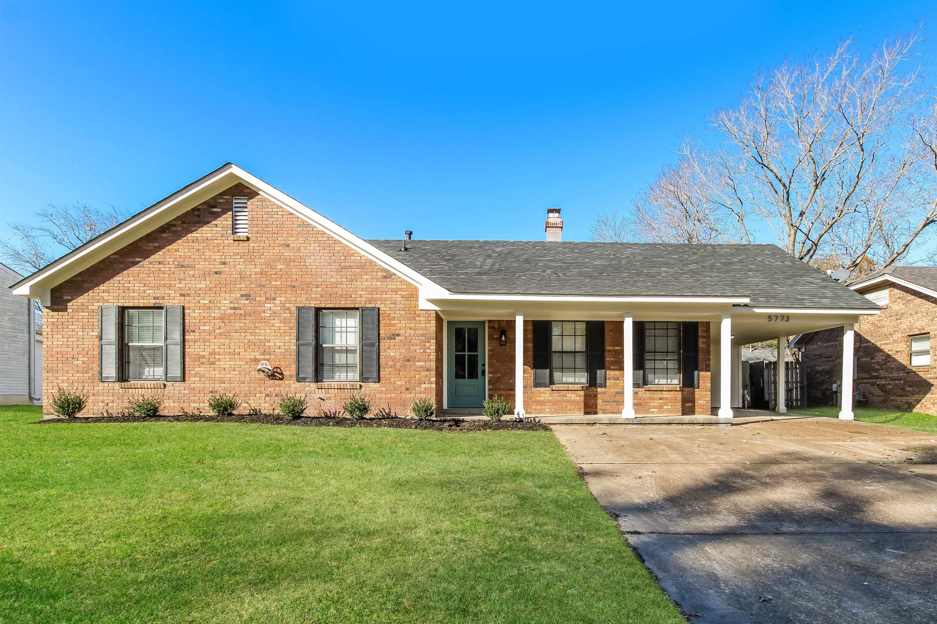 Ranch-style home featuring a porch, a front yard, and a carport