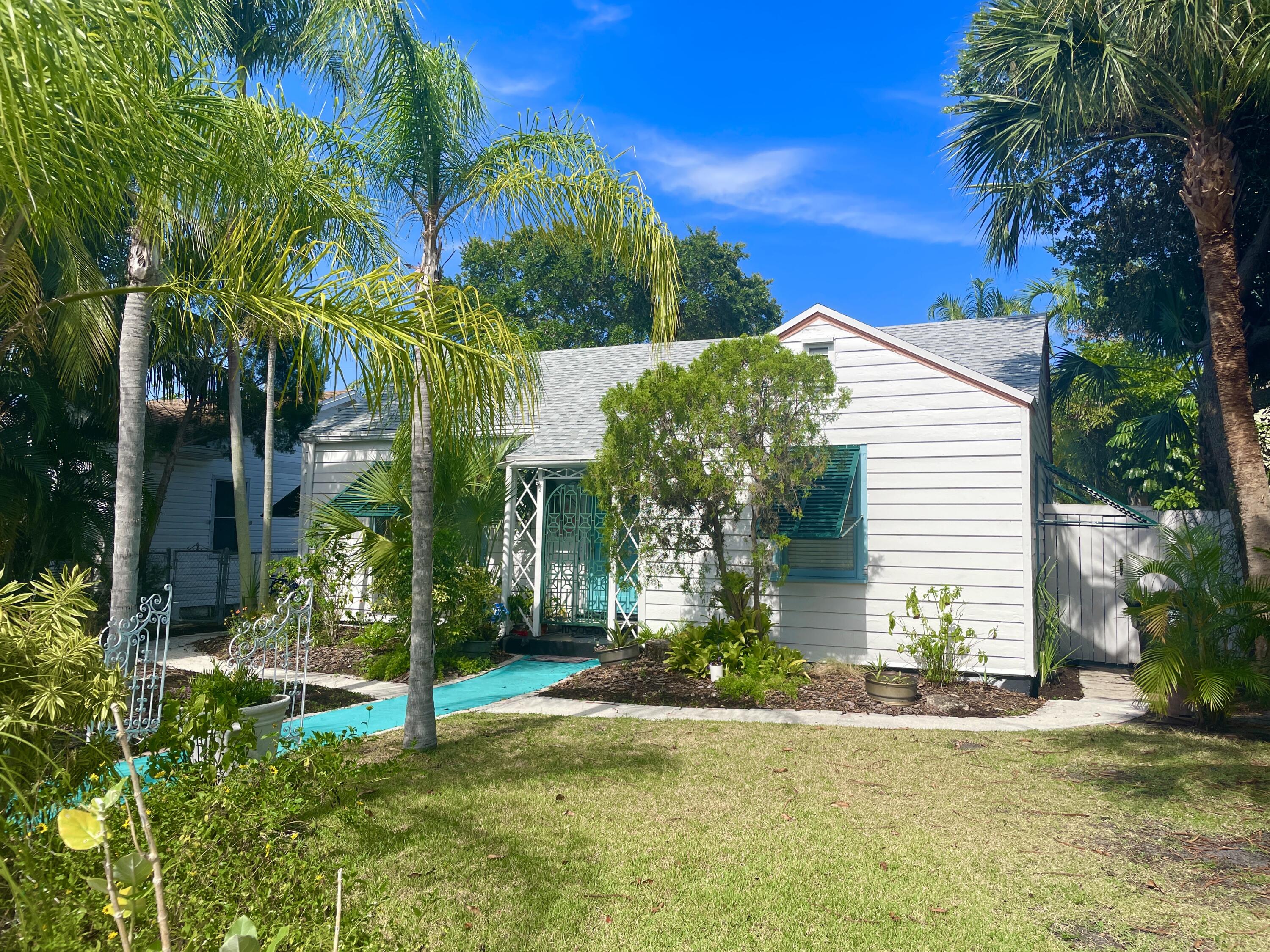 a view of a house with a yard and palm trees