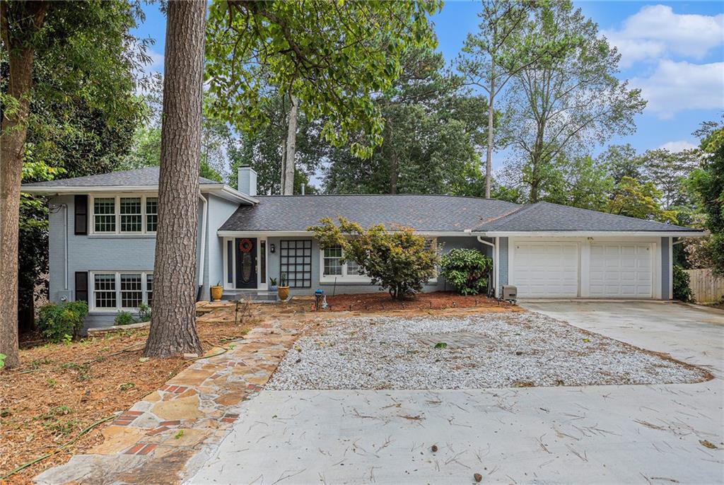 front view of a house with a dirt yard and large trees