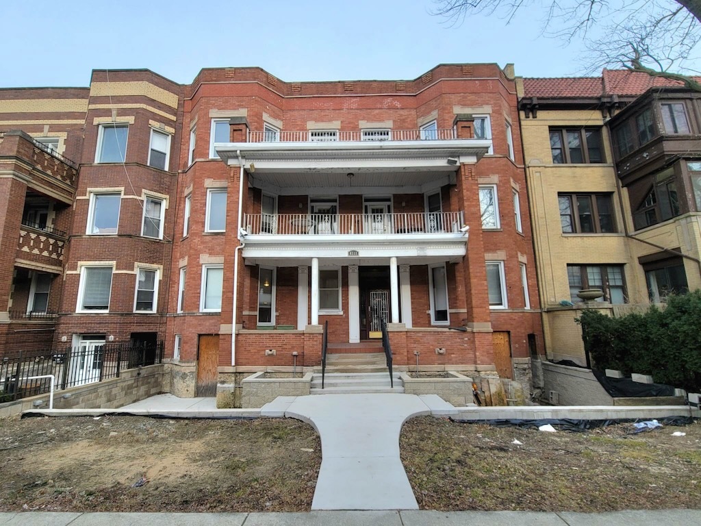 a front view of a residential apartment building with a yard and potted plants