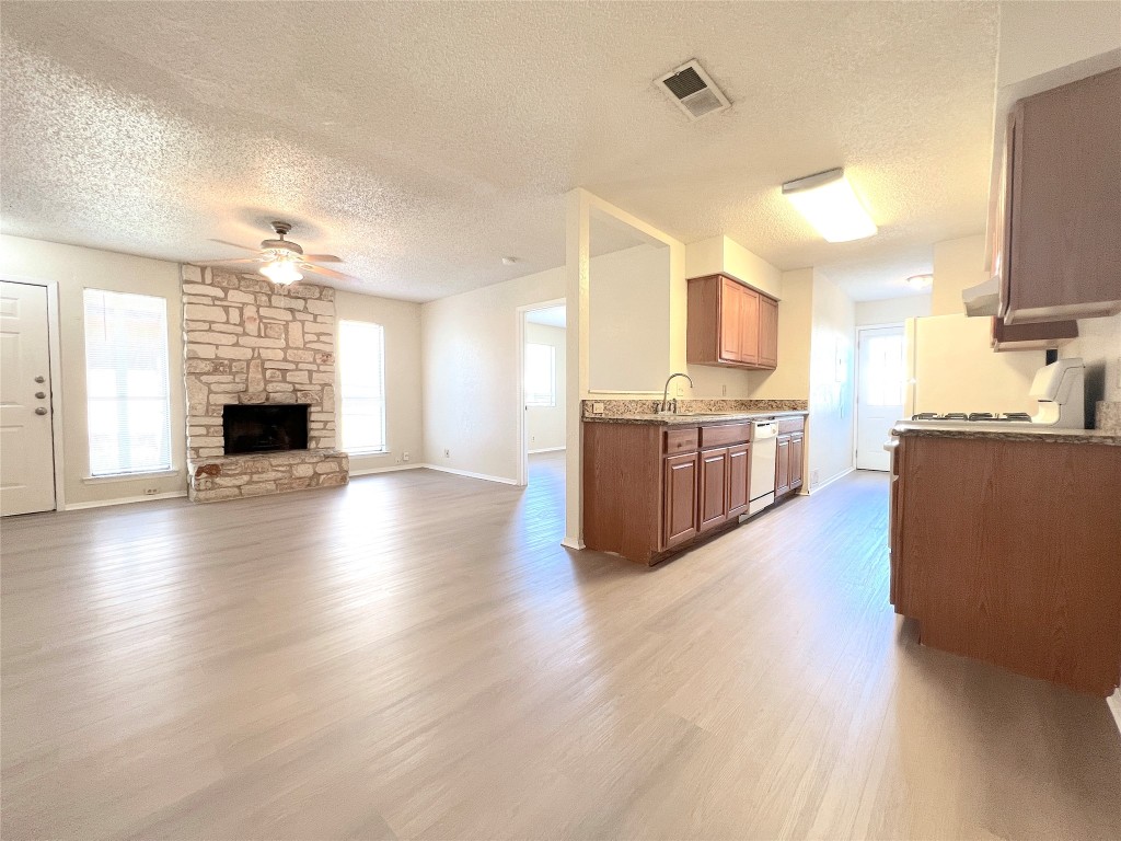 a living room with stainless steel appliances kitchen island granite countertop wooden floors and a fireplace