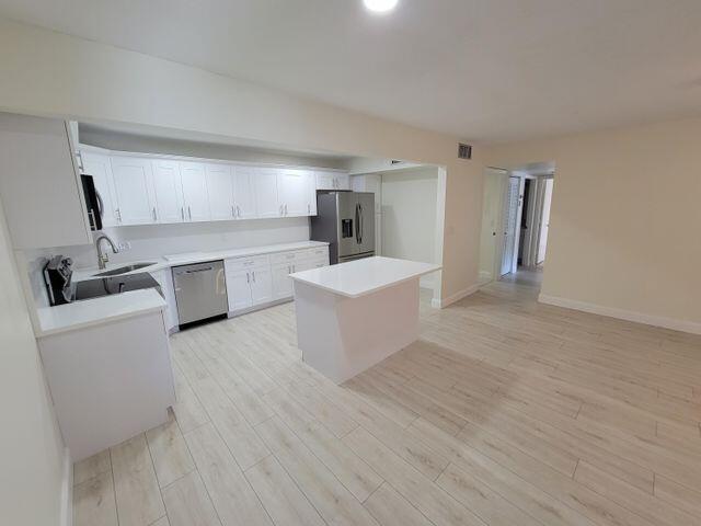 a view of a kitchen with a sink and dishwasher a refrigerator with white cabinets