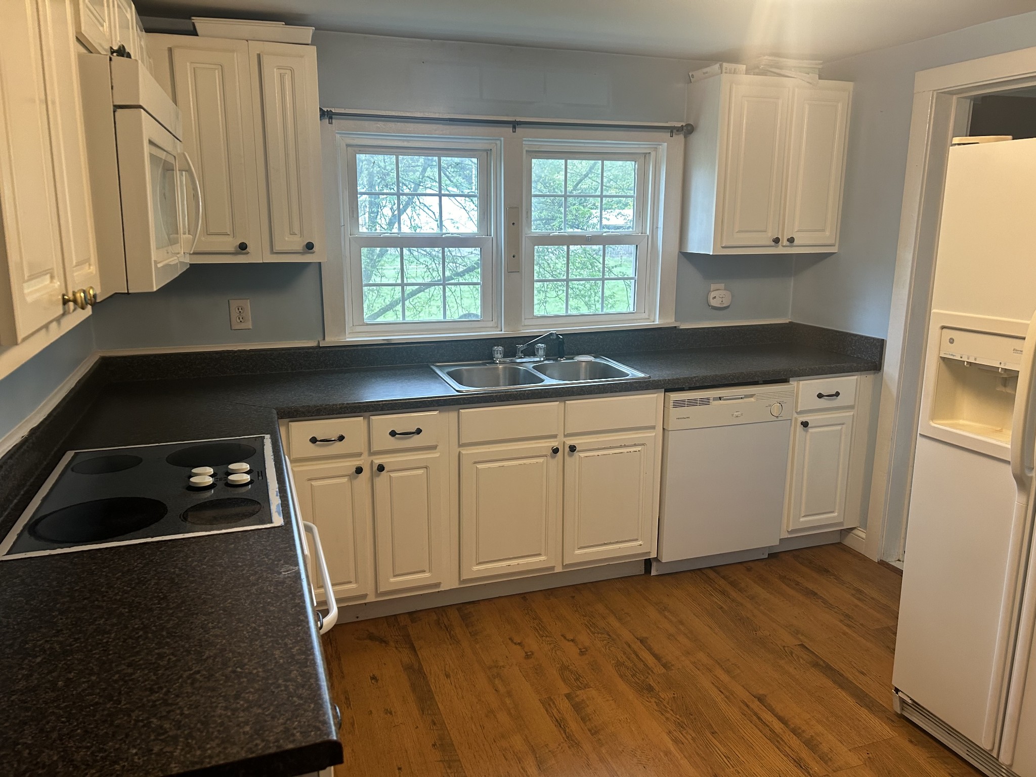 a kitchen with granite countertop a sink a stove a refrigerator and cabinets