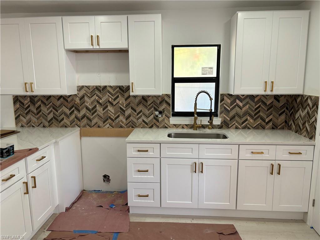 a kitchen with white cabinets and sink