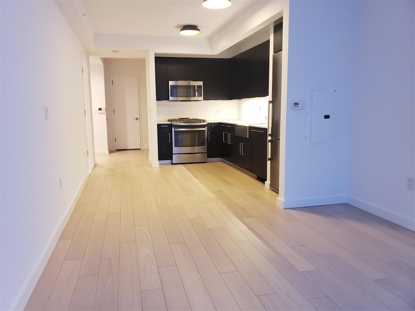 a view of kitchen with stainless steel appliances wooden floor and window