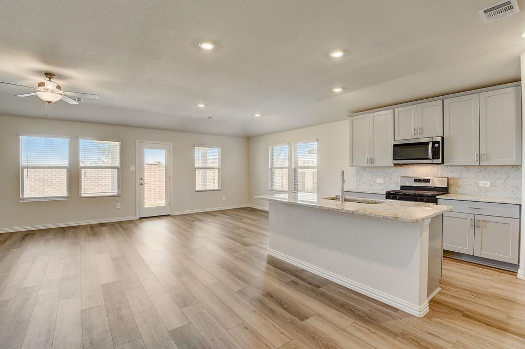 a large kitchen with cabinets wooden floor and stainless steel appliances