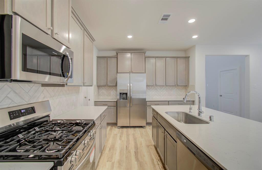 a kitchen with a sink stove top oven and refrigerator