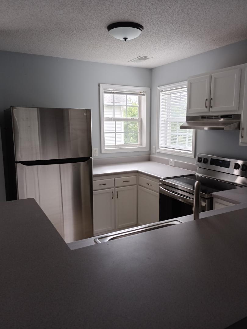 a kitchen with stainless steel appliances a refrigerator a stove a sink and a window