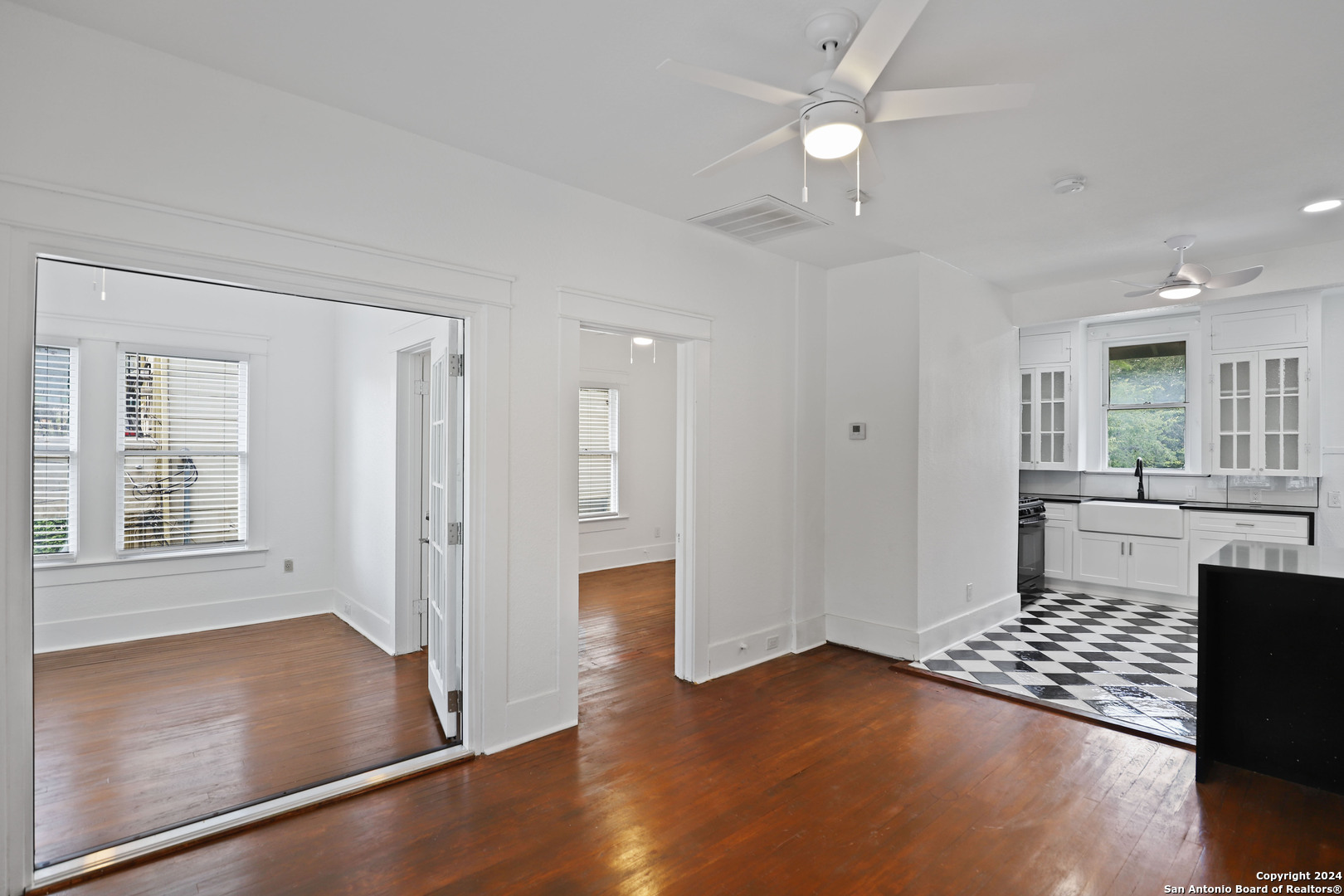 an empty room with wooden floor cabinet and windows