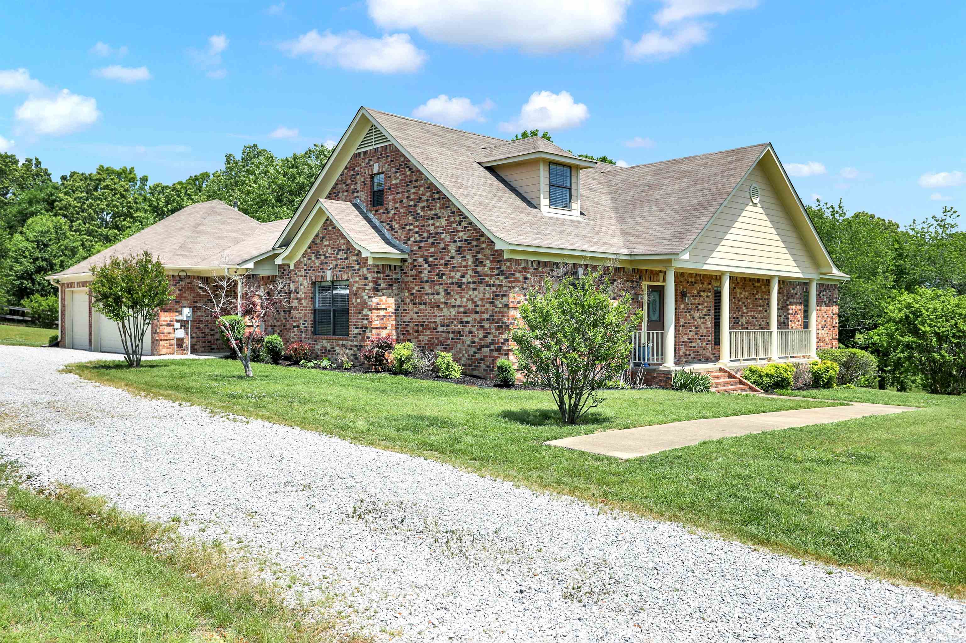 View of front facade with covered porch, a garage, and a front lawn