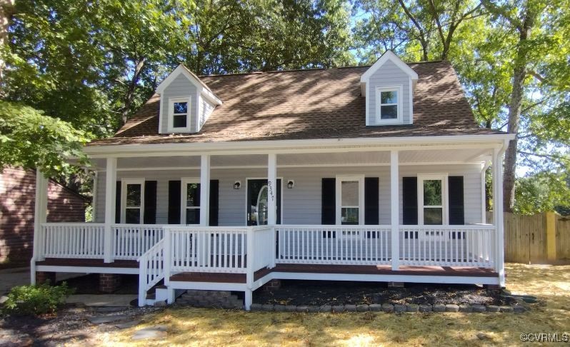 a view of a house with a small deck and a large tree