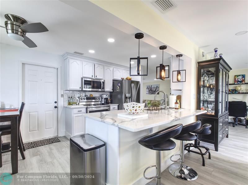 a kitchen with stainless steel appliances kitchen island granite countertop a table chairs and a refrigerator