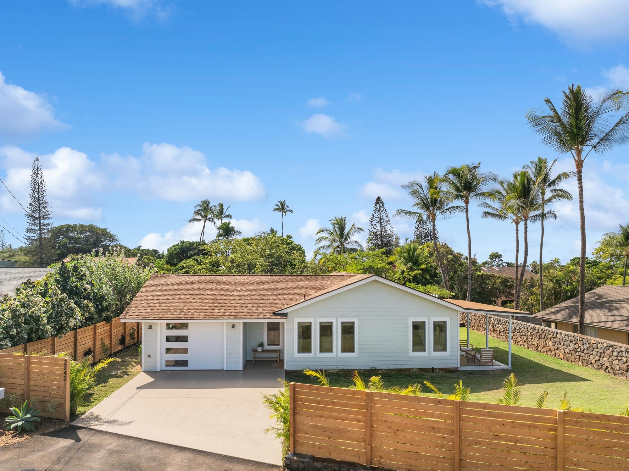 a view of a white house with a small yard and palm trees