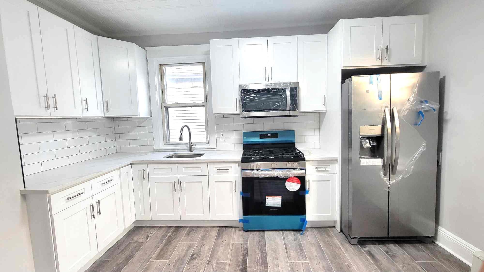 a kitchen with cabinets stainless steel appliances a sink and wooden floor