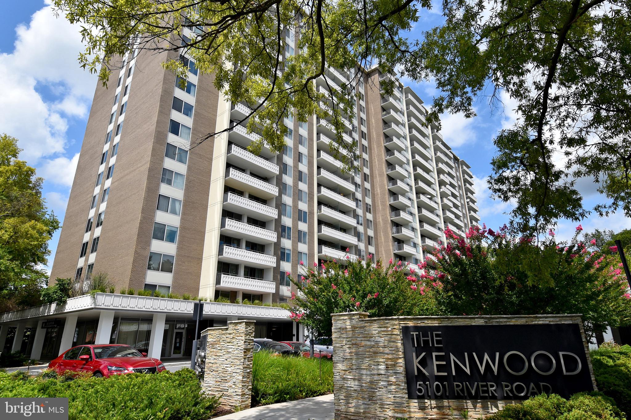 a front view of multi story residential apartment building with yard and sign board