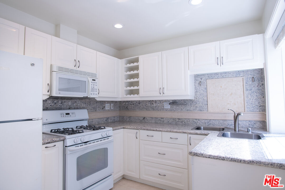 a kitchen with granite countertop white cabinets and white appliances