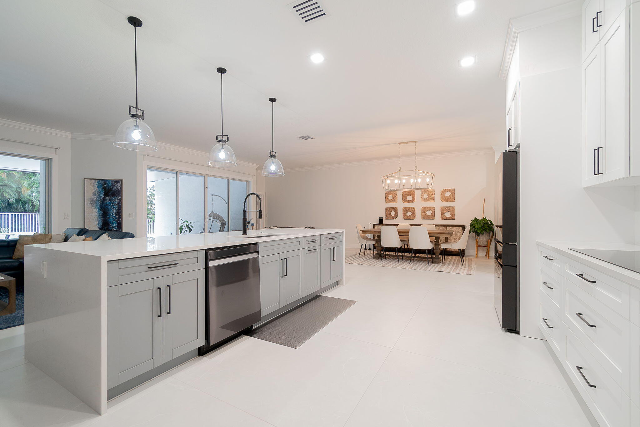 a large white kitchen with kitchen island a stove a sink a center island and windows