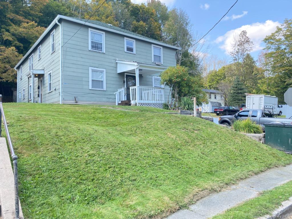 View of front of property featuring covered porch and a front yard