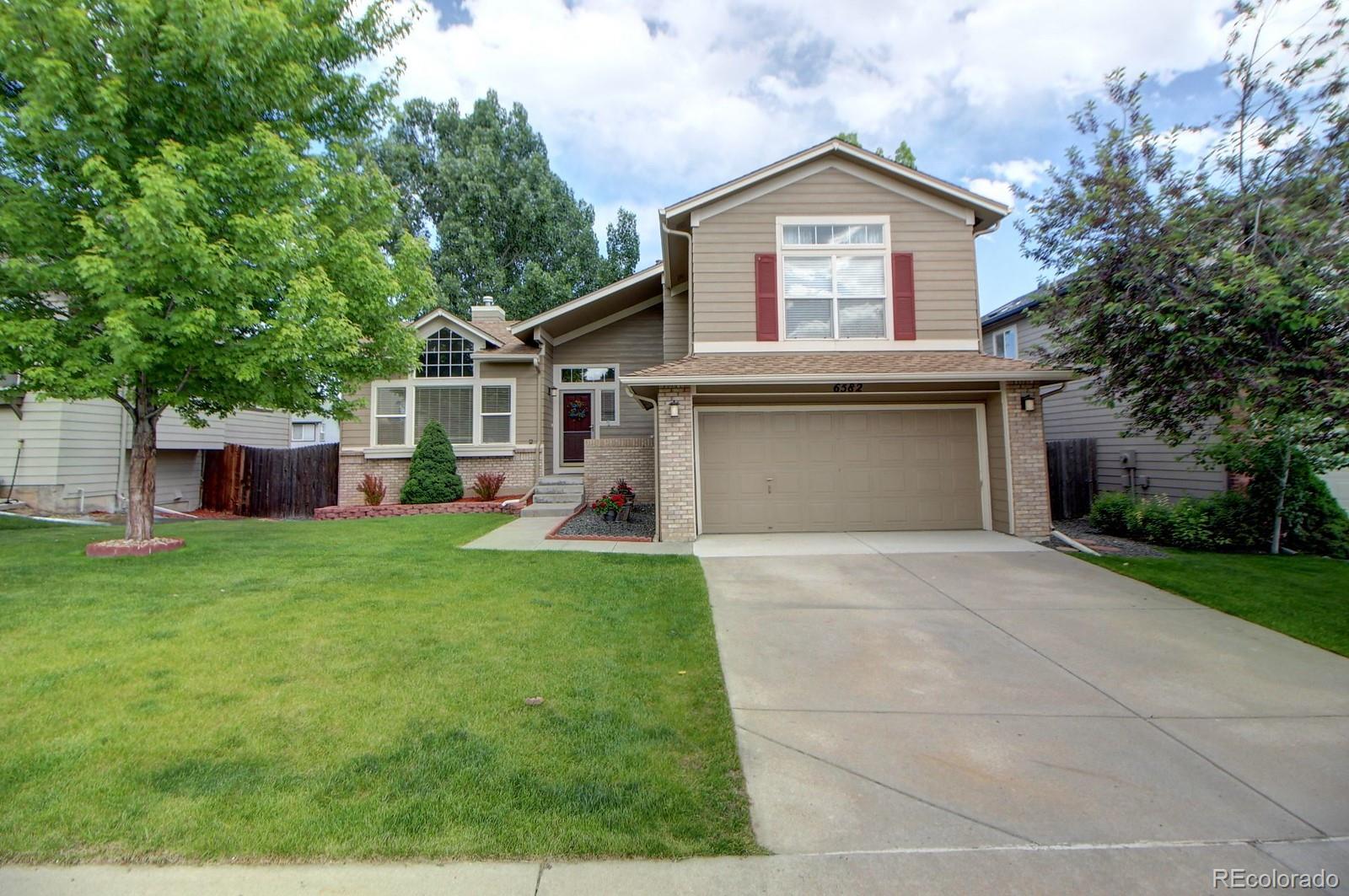 a front view of a house with a garden and trees