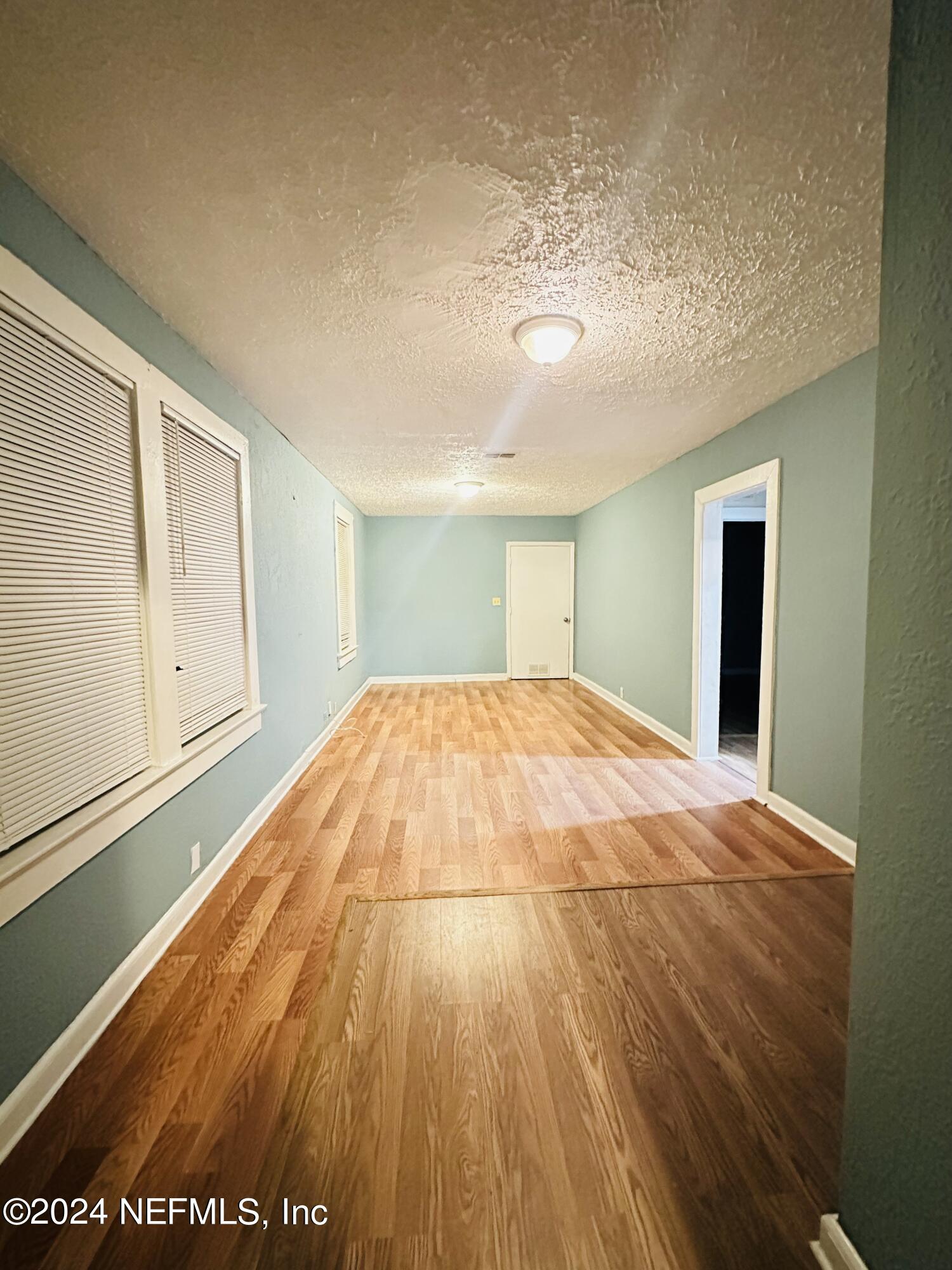 a view of an empty room with wooden floor