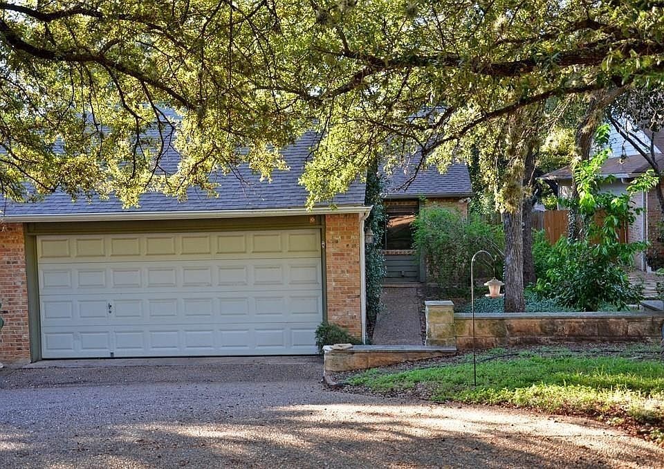 a view of a brick house with a large tree