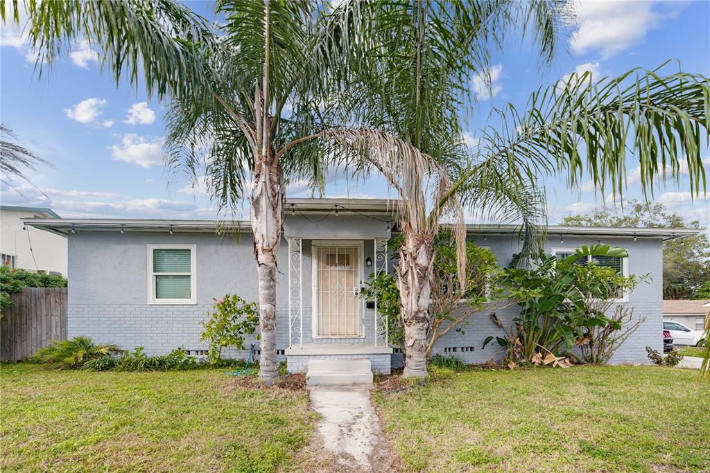 a front view of a house with a garden and palm trees