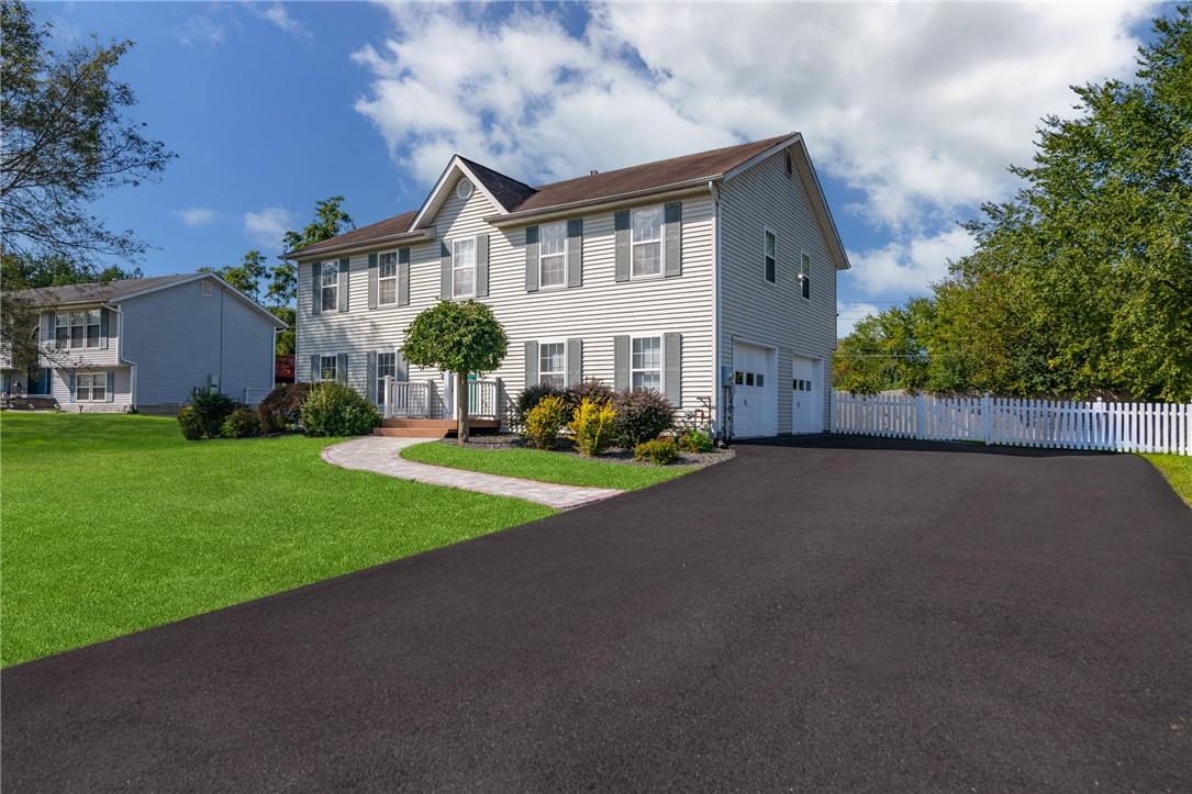 Colonial house featuring a garage and a front lawn