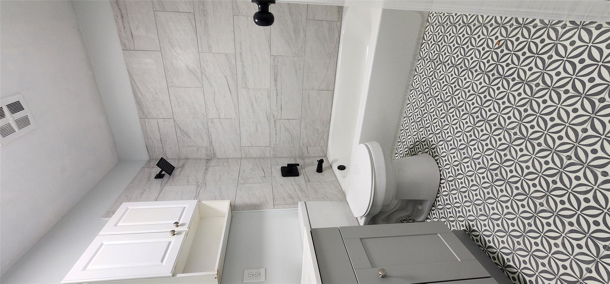 Full bathroom with tiled shower / bath combo, toilet, and vanity