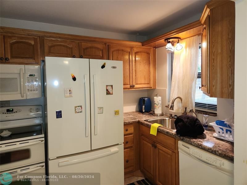 a kitchen with stainless steel appliances granite countertop a refrigerator a sink and white cabinets