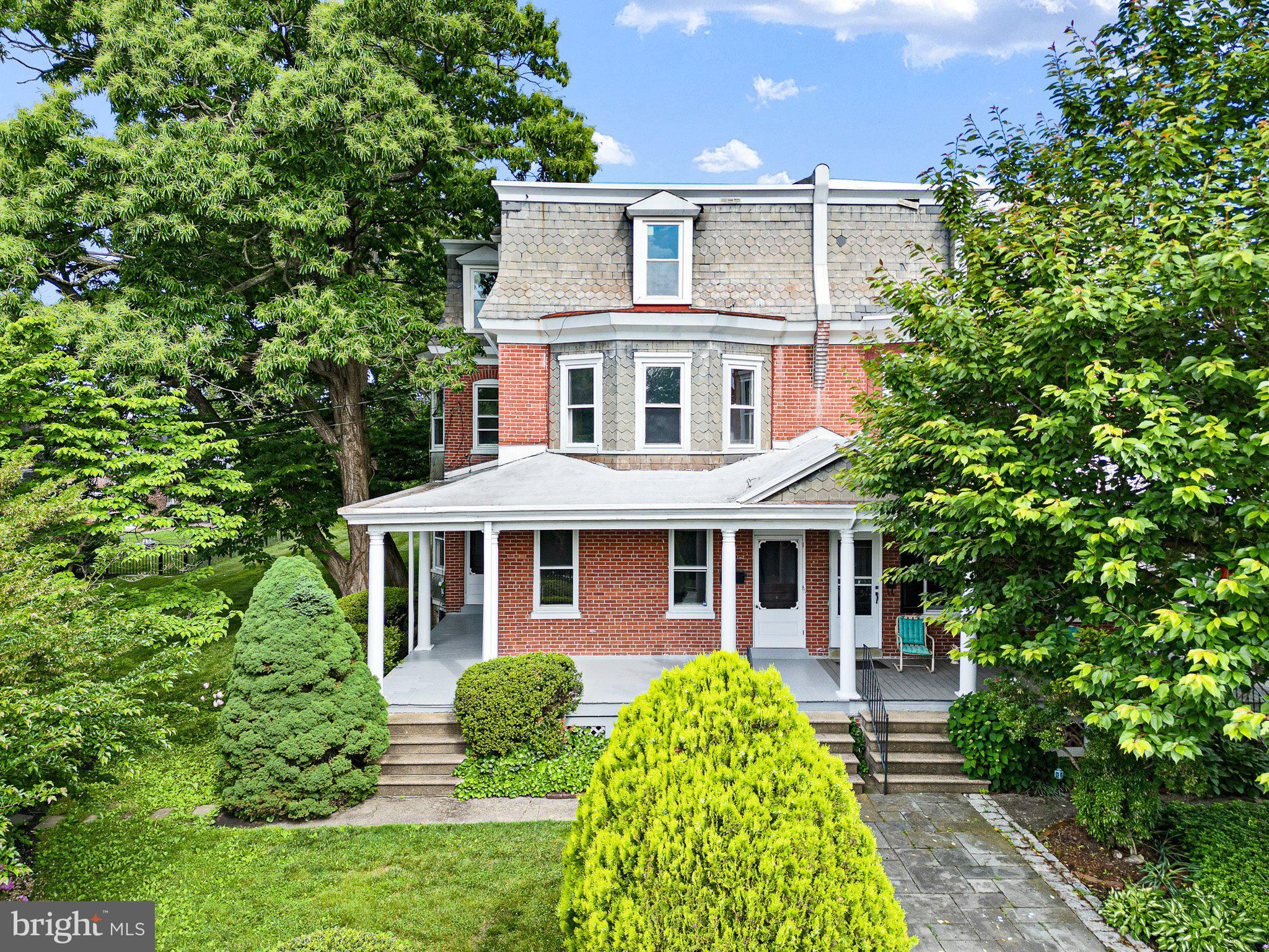 a front view of a house with garden and trees