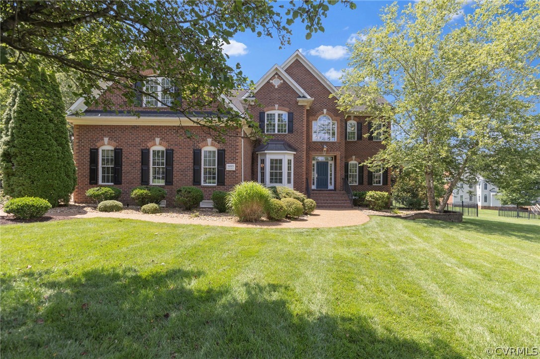 a front view of house with yard and trees in the background