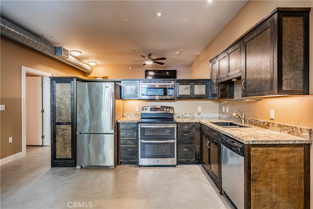 a kitchen with stainless steel appliances granite countertop a refrigerator a stove and a sink