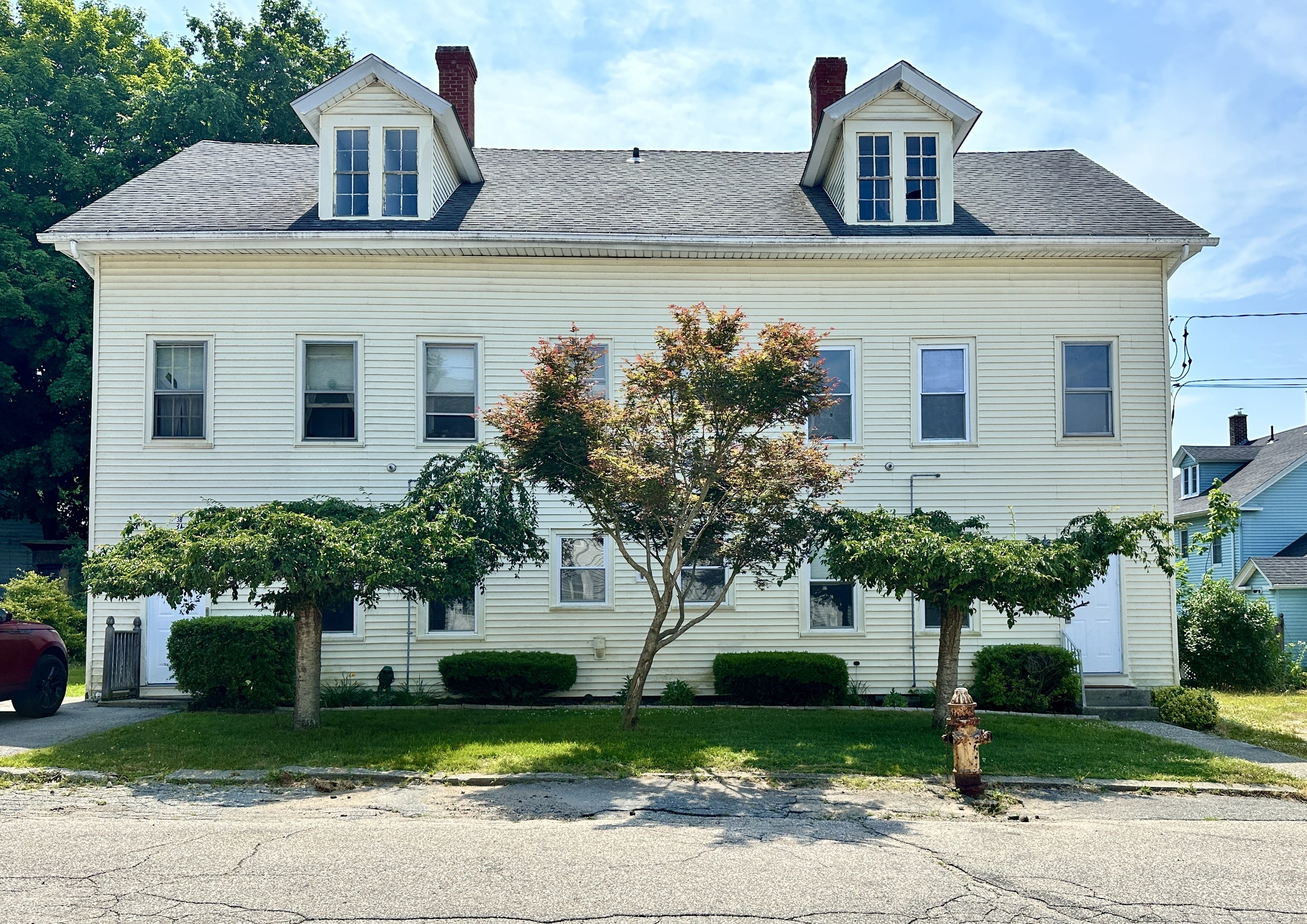 a front view of a house with a yard and trees