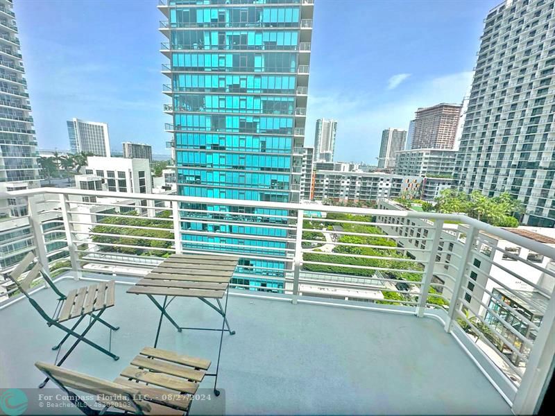 a view of a balcony with a floor to ceiling window next to a tall building