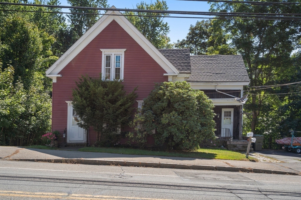 a view of a house with a yard plants and large tree