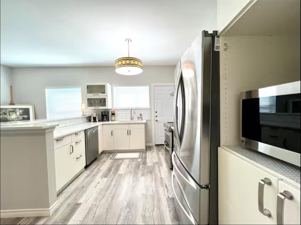 a kitchen with stainless steel appliances a refrigerator sink and white cabinets