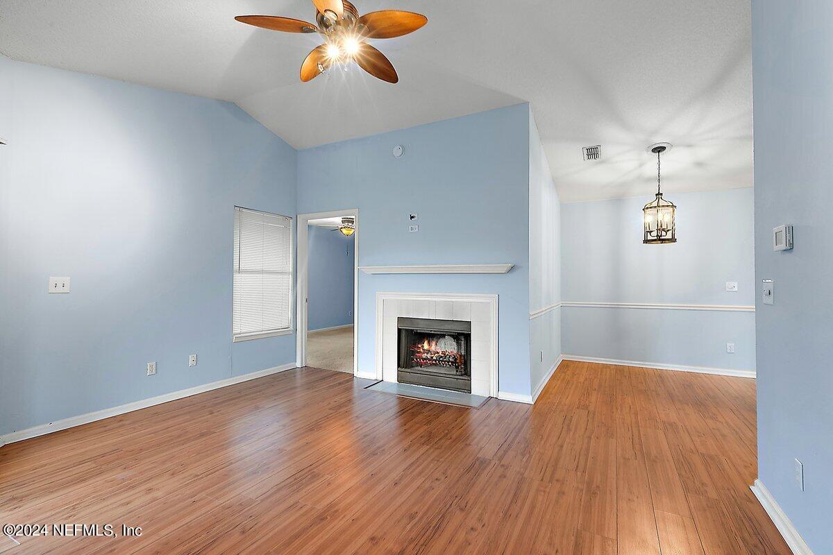 an empty room with wooden floor fireplace and windows