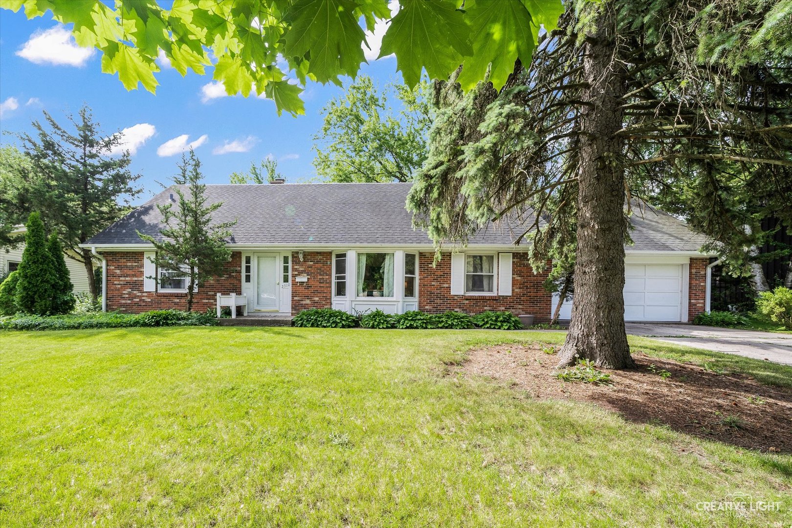 a front view of a house with a garden and trees