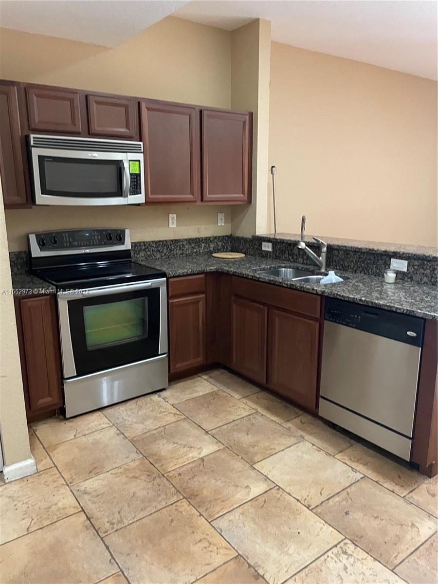 a kitchen with stainless steel appliances granite countertop a stove microwave and sink