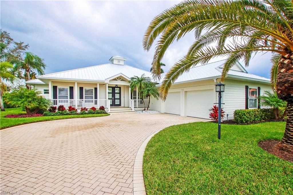 View of front of property with a porch, a garage, and a front lawn