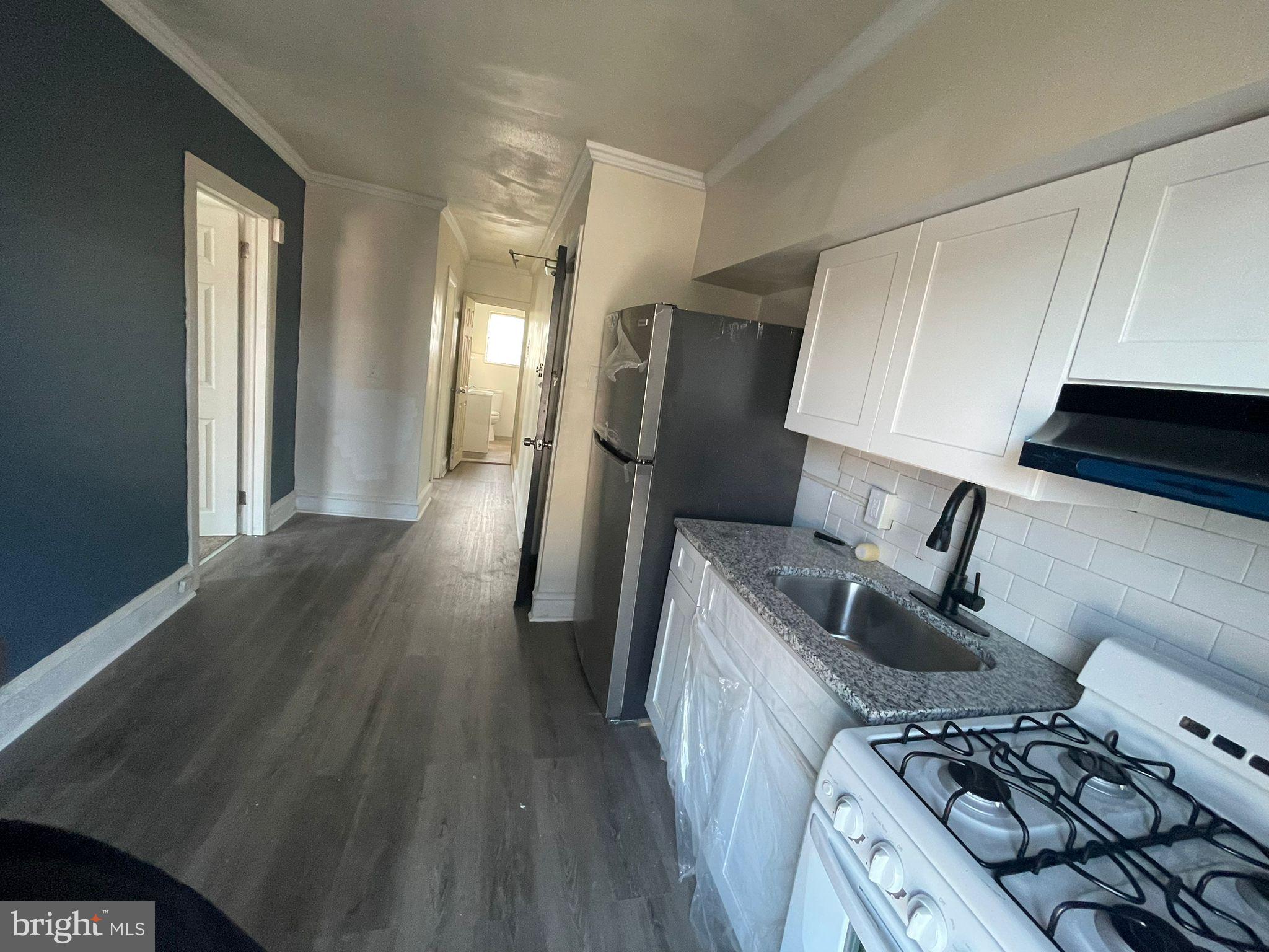 a kitchen with granite countertop a sink stove and refrigerator