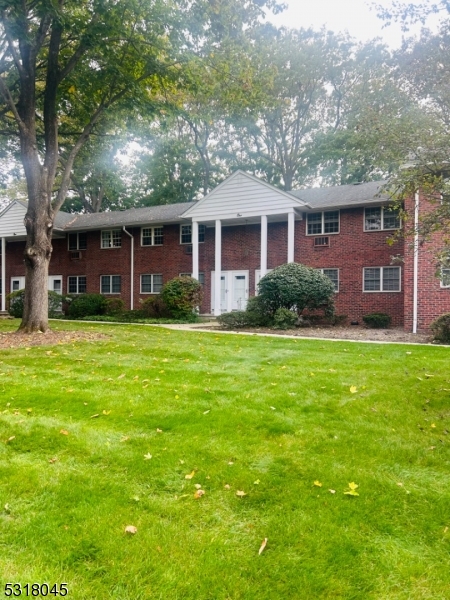 a view of a yard in front of a brick house with a large tree