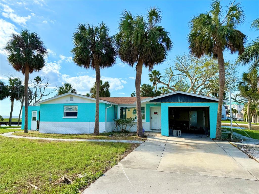 a front view of a house with a garden and palm trees