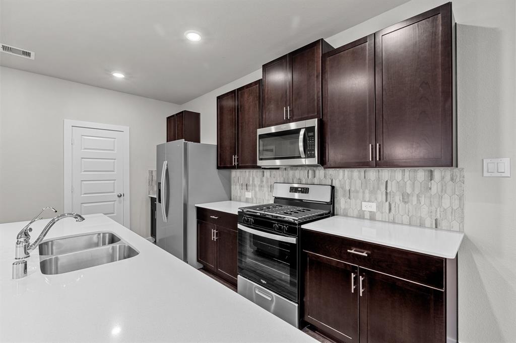 a kitchen that has a sink cabinets and stainless steel appliances