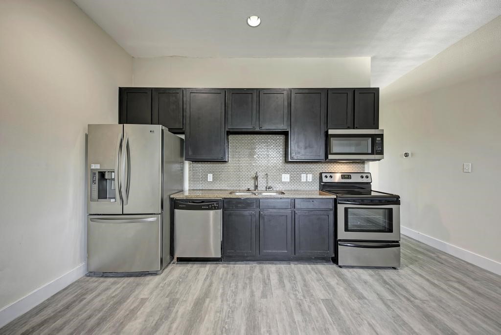 a kitchen with a refrigerator stove and wooden cabinets