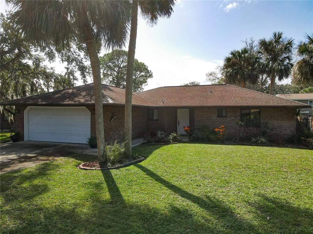 a view of a house with a yard and a large tree