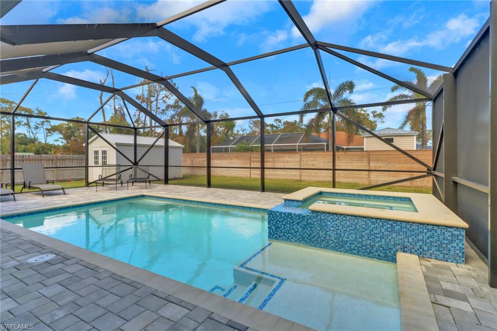 View of pool with a patio area, a storage shed, a lanai, and an in ground hot tub